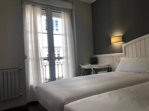 希洪Alda Miramar Rooms的卧室设有一张白色大床和一扇窗户。