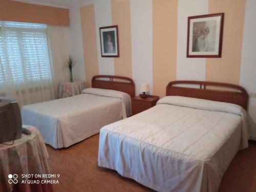 卡马里尼亚斯Pension Catro Ventos的一间酒店客房,设有两张床和电视