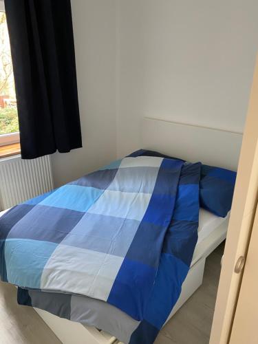 吕贝克Zentrale und schöne Ferienwohnung的窗户客房内的一张蓝色和白色的床