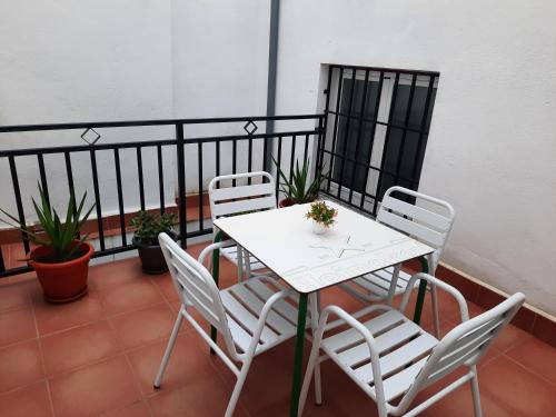 普拉森西亚Apartamentos Clavero 10的阳台上配有白色的桌椅