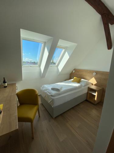 博斯科维采斯拉维亚酒店的一间卧室配有一张床和一把椅子,还有两个窗户