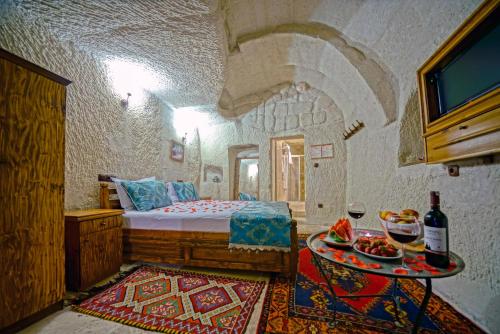 格雷梅爱丽舍洞穴酒店的一间卧室配有一张床和一张桌子,上面有食物