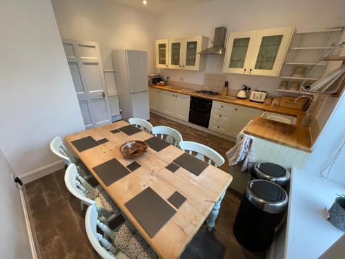 凯尔索Kelso cobbles的厨房配有木桌和白色橱柜。