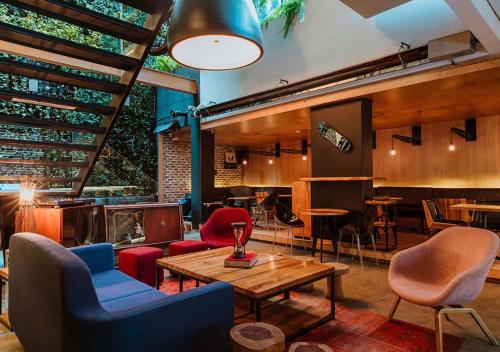 波哥大The Click Clack Hotel Bogotá的一间设有桌椅的房间和一间酒吧