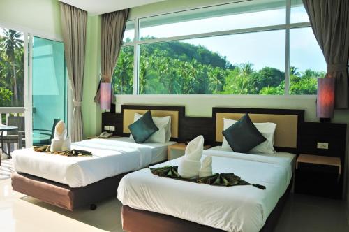 苏林海滩AM Surin Place - SHA Extra Plus的带大窗户的客房内的两张床