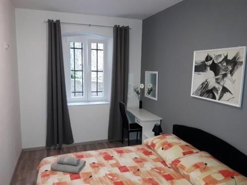 木洛希尼Apartments Vidulić的一间卧室配有一张床、一张书桌和一个窗户。