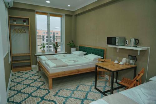 阿拉木图Halal Apart Hotel Almaty的一间卧室配有一张床、一张桌子和一个窗户。