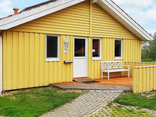 奥特尔恩多夫12 person holiday home in Otterndorf的黄色的房子,有白色的门和长凳