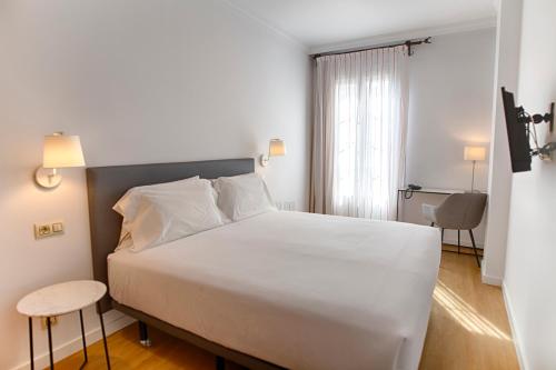 马拉加Sercotel Tribuna Málaga的卧室设有一张白色大床和一扇窗户。