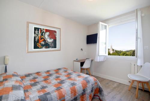卢尔德山堡酒店的一间卧室配有一张床、一个窗口和一张书桌