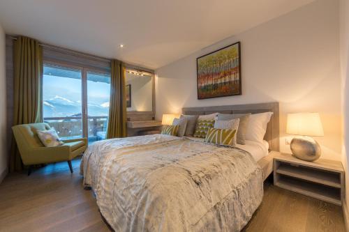南达Apartment La Forêt 2 - Spa access的一间卧室设有一张大床、一把椅子和窗户。