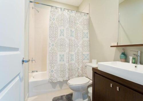 拿骚Luxury Venetian Condo的浴室配有淋浴帘、卫生间和盥洗盆。