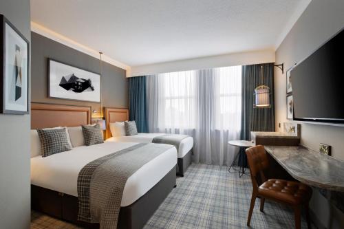 爱丁堡Leonardo Royal Hotel Edinburgh的酒店客房配有两张床和一张书桌