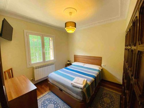 萨马涅戈SagastiEnea Villa con Piscina y Tenis en la Rioja的一间卧室配有一张床、一张桌子和一个窗户。