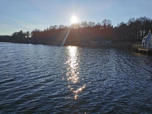 普劳西Gasthof & Hotel Heidekrug的享有湖泊美景,阳光在水面上反射