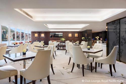 香港皇家太平洋酒店的一间带桌子和白色椅子的餐厅