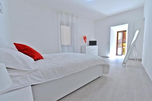 切雷西奥港Casa CarMa的白色卧室配有一张带红色枕头的大白色床