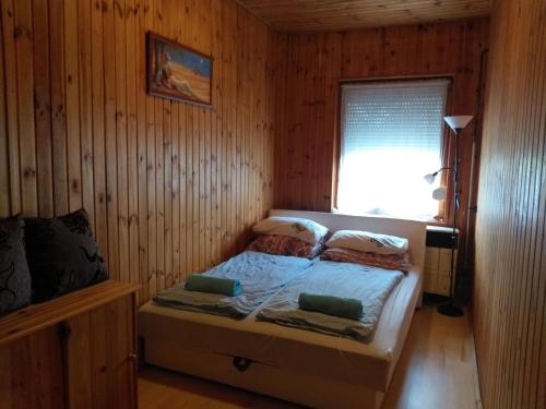 波罗斯洛Tavasz Nyaraló的木制客房内的一间卧室,配有一张床