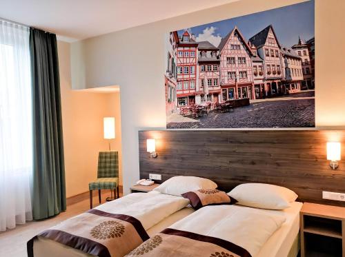 美因茨美因茨酒店的两张位于酒店客房的床,墙上挂着照片