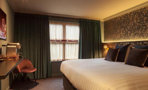 贝尔法斯特House Belfast Hotel的酒店客房设有一张床、一张书桌和窗户。