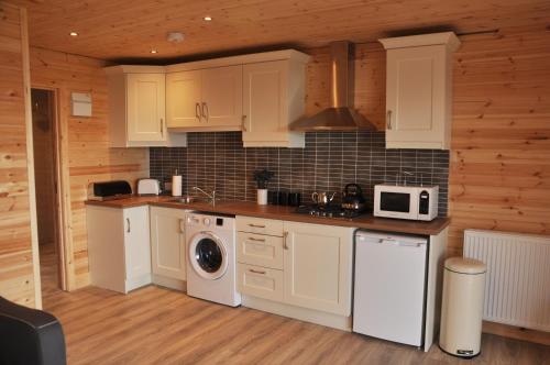 格林卡斯尔FOYLE VIEW CABIN的厨房配有白色橱柜、洗衣机和烘干机