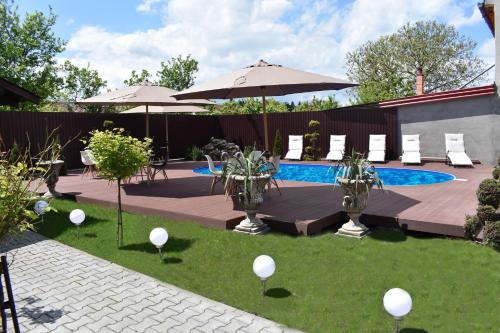 图尔达Pensiunea Casa Zece的后院设有游泳池、椅子和遮阳伞