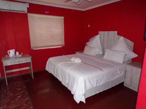 开普敦Khaya B&B的一间红色的卧室,配有白色的床和红色的墙壁
