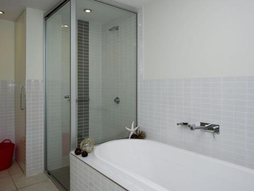 耐莉湾蓝上蓝高级一室公寓1271度假屋的带浴缸和玻璃淋浴间的浴室。