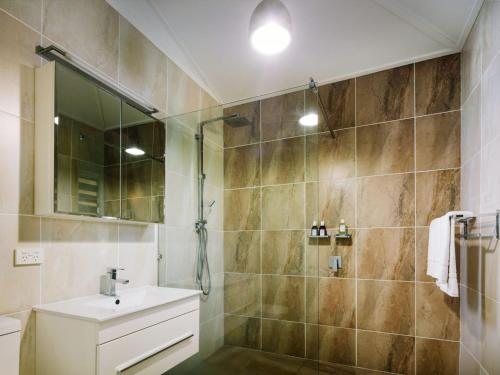 耐莉湾小树丛度假屋的带淋浴、盥洗盆和镜子的浴室