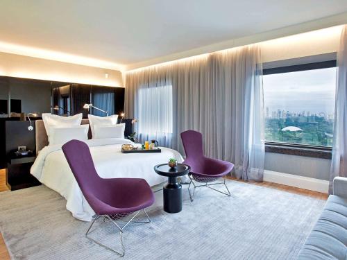 圣保罗铂尔曼圣保罗伊比拉普埃拉酒店的酒店客房,配有一张床和两张紫色椅子