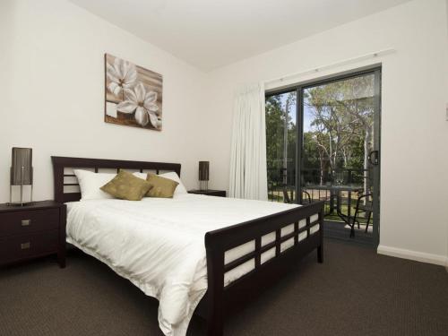 阿卡狄亚伍德维尔海滩联排别墅6号度假屋的一间卧室设有一张大床和一个大窗户