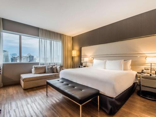 圣保罗圣保罗维拉奥林匹亚铂尔曼酒店的酒店客房设有一张大床和一张沙发。
