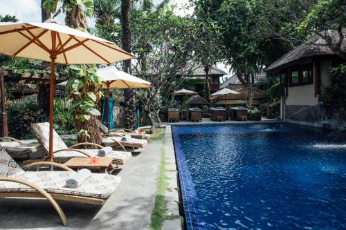 坎古Hotel Tugu Bali - CHSE Certified的毗邻度假酒店的带椅子和遮阳伞的游泳池