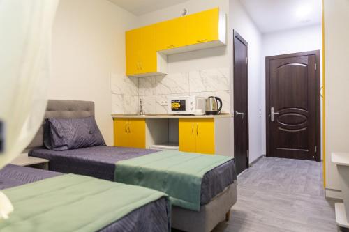 敖德萨泽尼斯酒店的带两张床的房间和带黄色橱柜的厨房