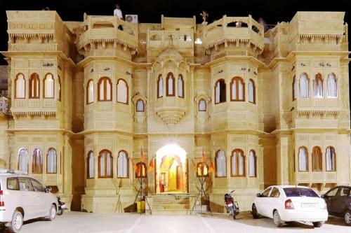斋沙默尔Hotel Lal Garh Fort And Palace的一座大型建筑,前面有汽车停放