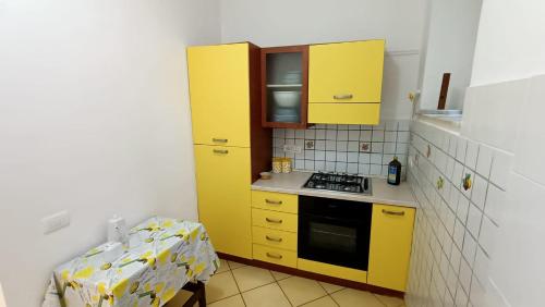 马拉泰亚Casa vacanze da Cristina app B的一间设有黄色橱柜和一张桌子的小厨房