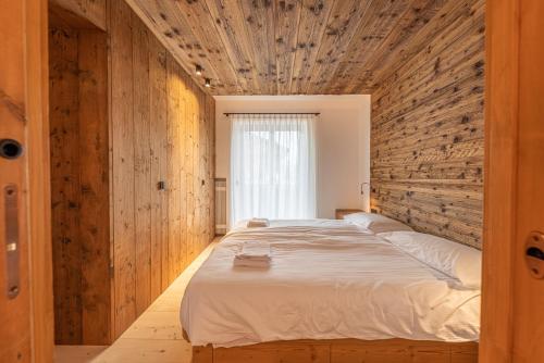 科尔蒂纳丹佩佐Casa del Lupo的一间卧室设有一张带木墙的大床