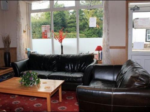 KirtlebridgeThe Village Inn的客厅配有黑色真皮沙发和桌子