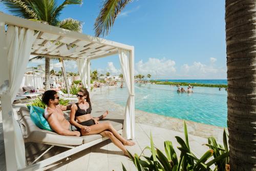 艾库玛尔TRS Yucatan Hotel - Adults Only的两个比基尼女人坐在游泳池边的秋千上