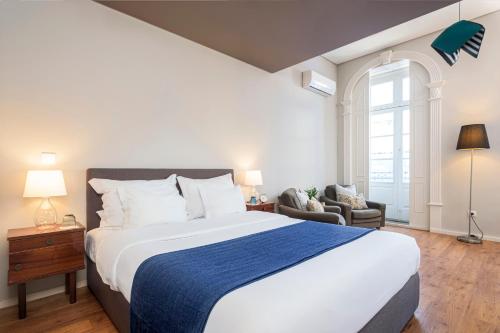 波尔图B闹市区客人酒店的一间卧室配有一张带蓝色毯子的大床