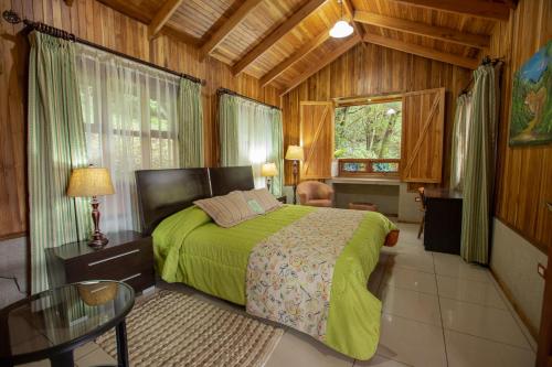 蒙泰韦尔德哥斯达黎加Los Pinos Cabins & Reserve的木制客房内的一间卧室配有一张绿色的床