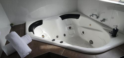 德尼利昆Centrepoint Motel Deniliquin的浴室设有白色浴缸,配有毛巾