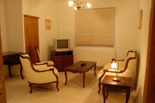 Galata翁格瑞套房酒店的客厅配有椅子、桌子和电视