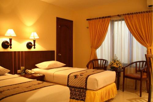 梭罗男爵英达酒店的酒店客房带两张床和一张桌子以及椅子。