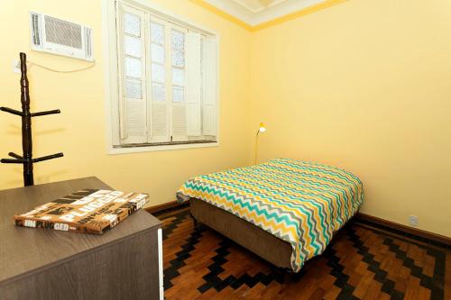 里约热内卢Casa Saga - All Suites的一间卧室配有一张床、一张桌子和一个窗户。