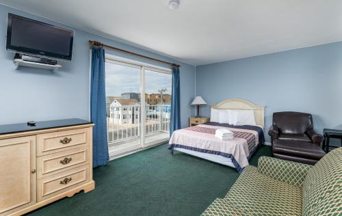 希塞德高地Hotel Charlee Villas Beach Hotel Oceanblock的一间卧室配有一张床、一台电视和一把椅子