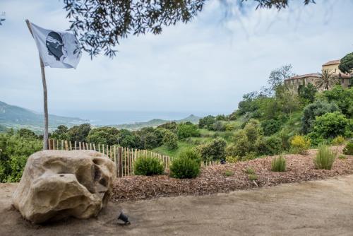 Sari-dʼOrcinoTerre de Maquis, maison d'hôtes vue mer Corse的摇滚旁边的柱子上的旗帜