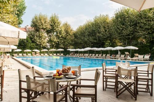 维亚雷焦Grand Hotel Royal的游泳池旁的桌椅