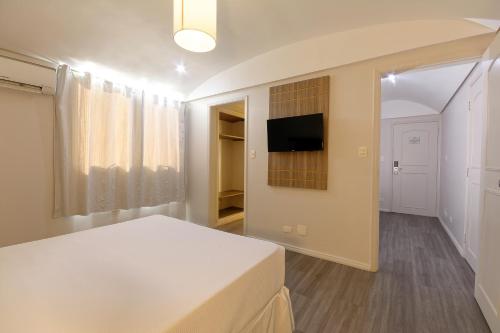 圣保罗Fênix Hotel Moema的一间卧室配有一张床,墙上配有电视