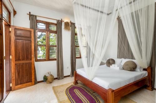 布韦朱KIMA Serviced Beach House & Suites的一间卧室配有带窗帘的床和门